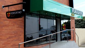 A modern hotel with a brick facade, large windows, and a green awning. - Portofino Hotel (Teresina)