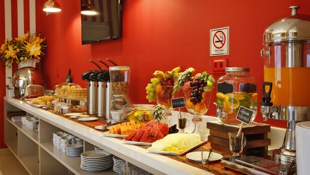 A buffet with various fruits and beverages, a coffee machine, and a no-smoking sign on the wall. - Portofino Hotel (Teresina)