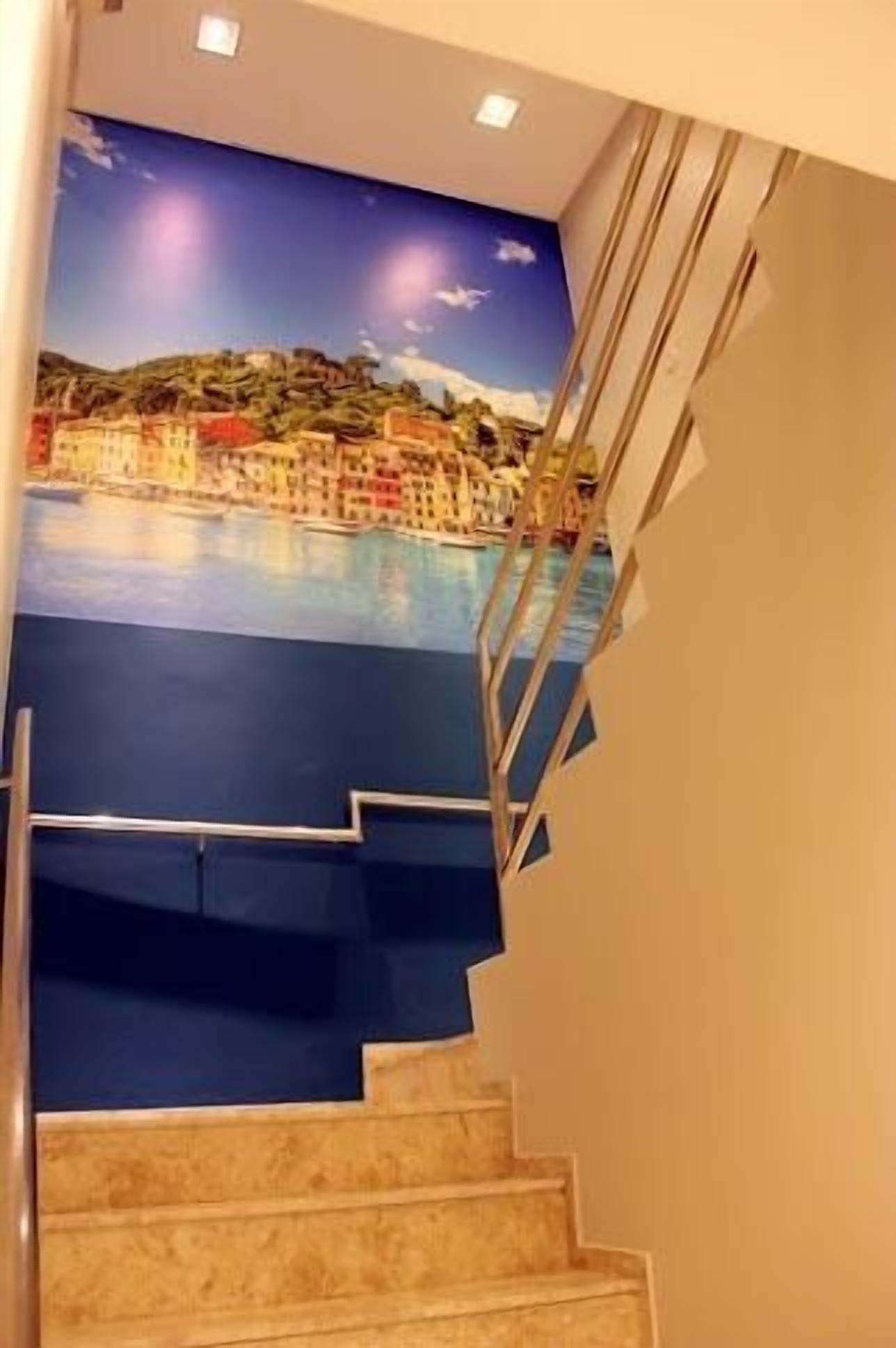 Una escalera con un muro azul y un mural de un pueblo costero.