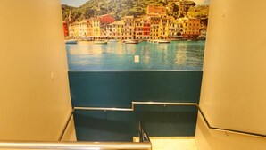 A staircase with a view of a coastal town through a mural. - Portofino Hotel (Teresina)