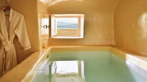 A bathtub with a view of mountains through a window. - OIA Unique Homes by K&K (Santorini)