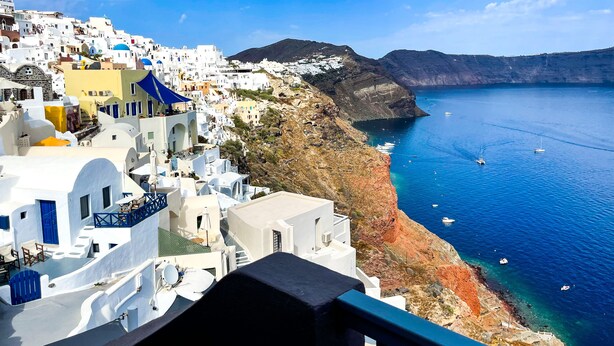 A coastal town with white buildings, a clear blue sea, and boats. - OIA Unique Homes by K&K (Santorini)