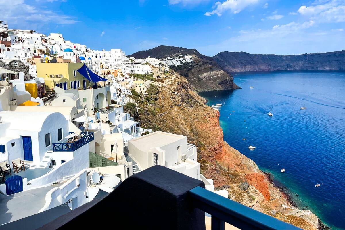 Un pueblo costero con edificios blancos, mar azul cristalino y barcos.