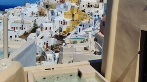 A balcony with a hot tub overlooking a coastal town with white buildings and a clear blue sky. - OIA Unique Homes by K&K (Santorini)