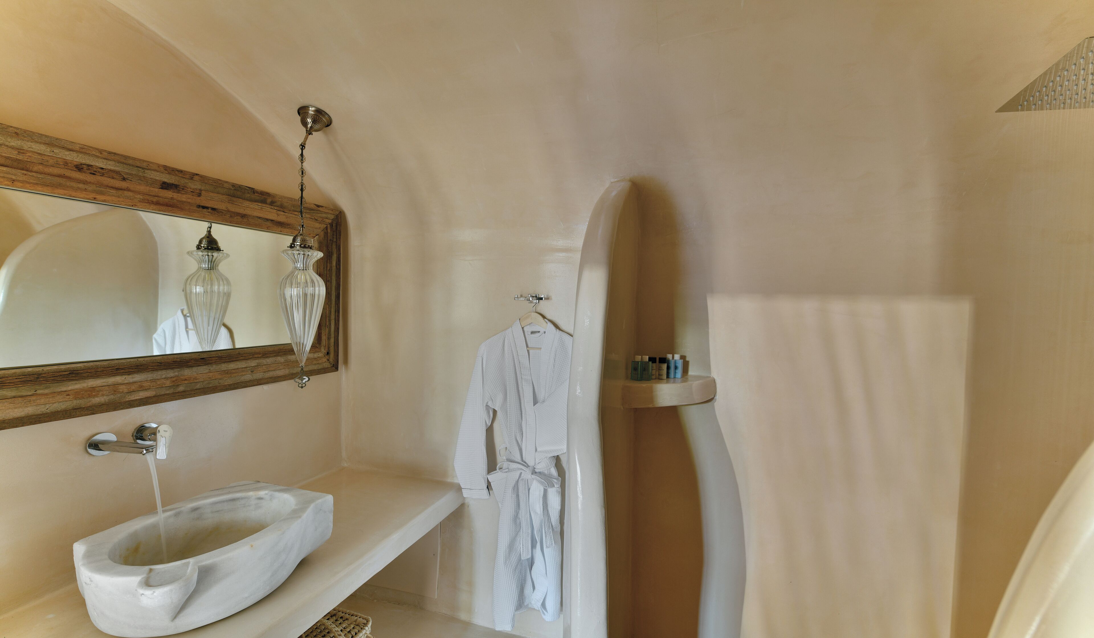 A bathroom with a marble sink, a hanging glass light fixture, a towel rack, and a surfboard leaning against the wall.