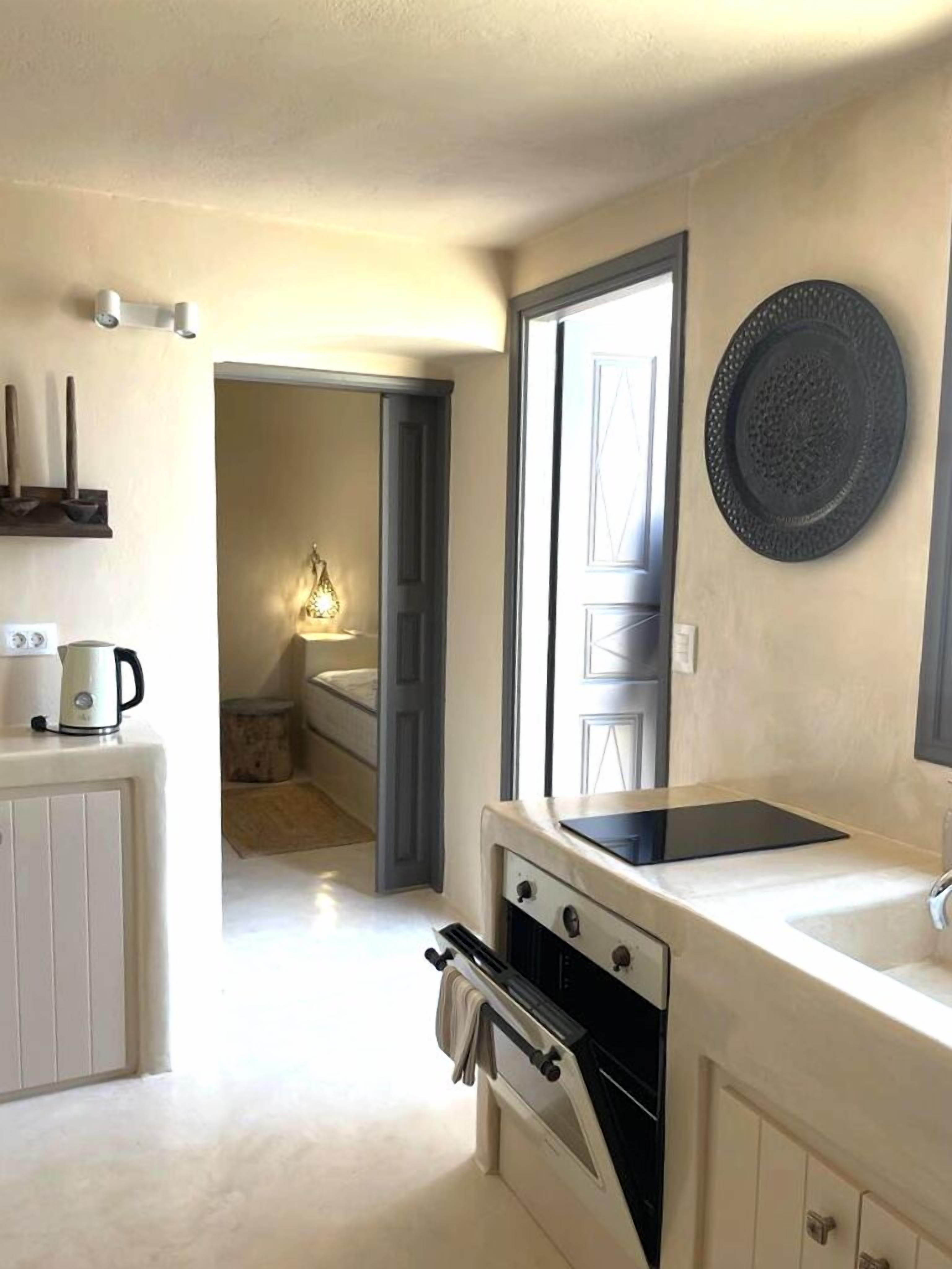 A modern kitchen with a built-in oven, a stovetop, and a sink. There is a window with a view of the outside.