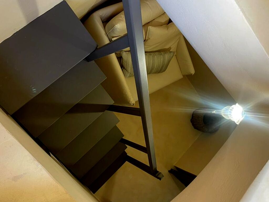 A staircase with a metal handrail and beige walls.