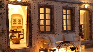 A cozy room with a sofa, a table with candles, and a view of a kitchen and dining area through a window. - OIA Unique Homes by K&K (Santorini)