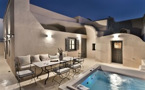 An outdoor seating area with a table and chairs, a small pool, and a door with a window. - OIA Unique Homes by K&K (Santorini)
