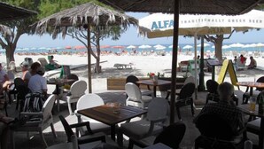 Un espace extérieur aménagé avec des tables, des chaises, des parasols et une vue sur la plage.