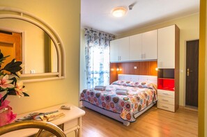 Un dormitorio con cama, escritorio, espejo y armario.