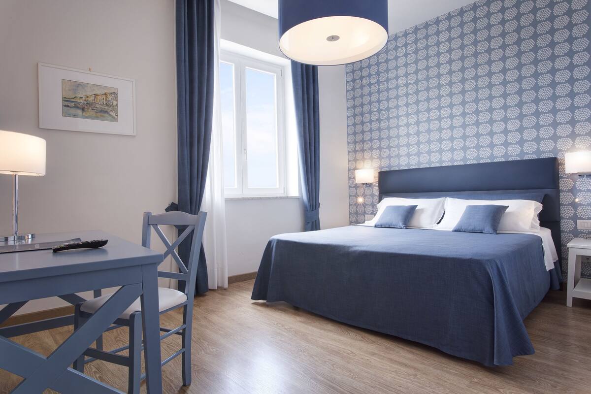 A bedroom with a bed, a desk, and a chair.