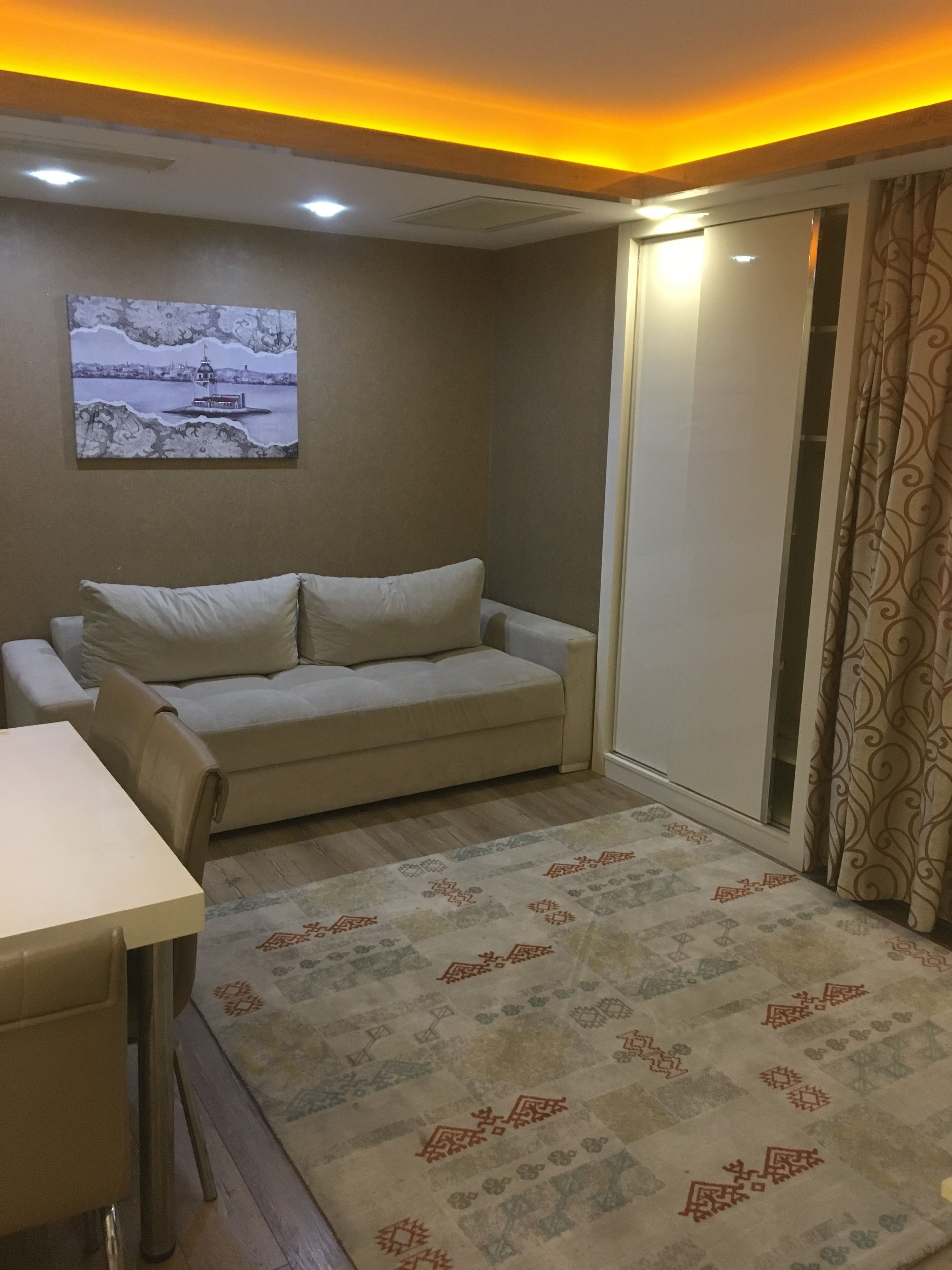 A room with a sofa, a table, a patterned rug, and a painting on the wall.