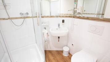 Un bagno moderno con box doccia in vetro, un lavandino bianco e un water.