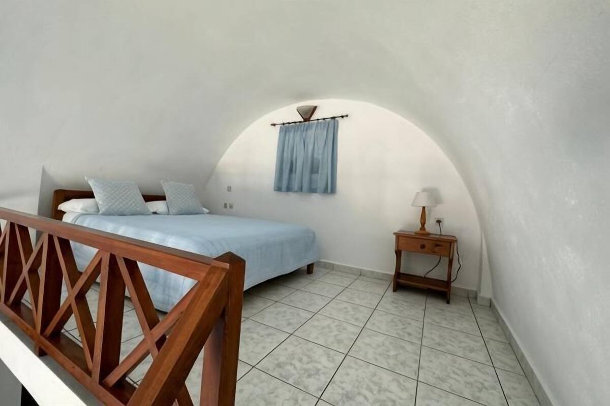 A bedroom with a bed, a nightstand, a lamp, and a window with curtains.