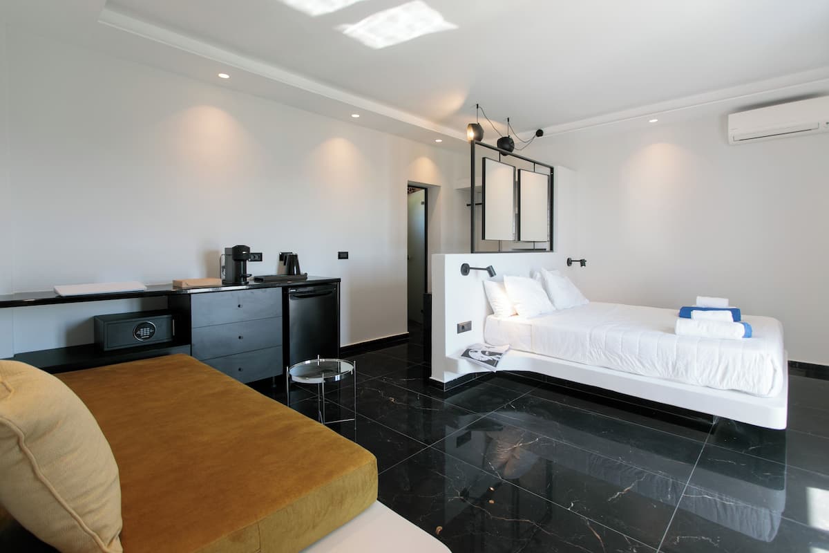 A modern hotel room with a bed, a desk, a chair, and a small table.
