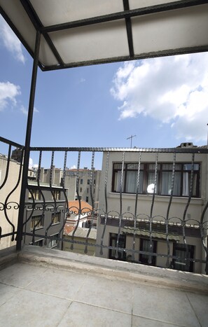 A balcony with a metal railing, a tiled floor, and a view of buildings in the background. - Entes Apart (Istanbul)