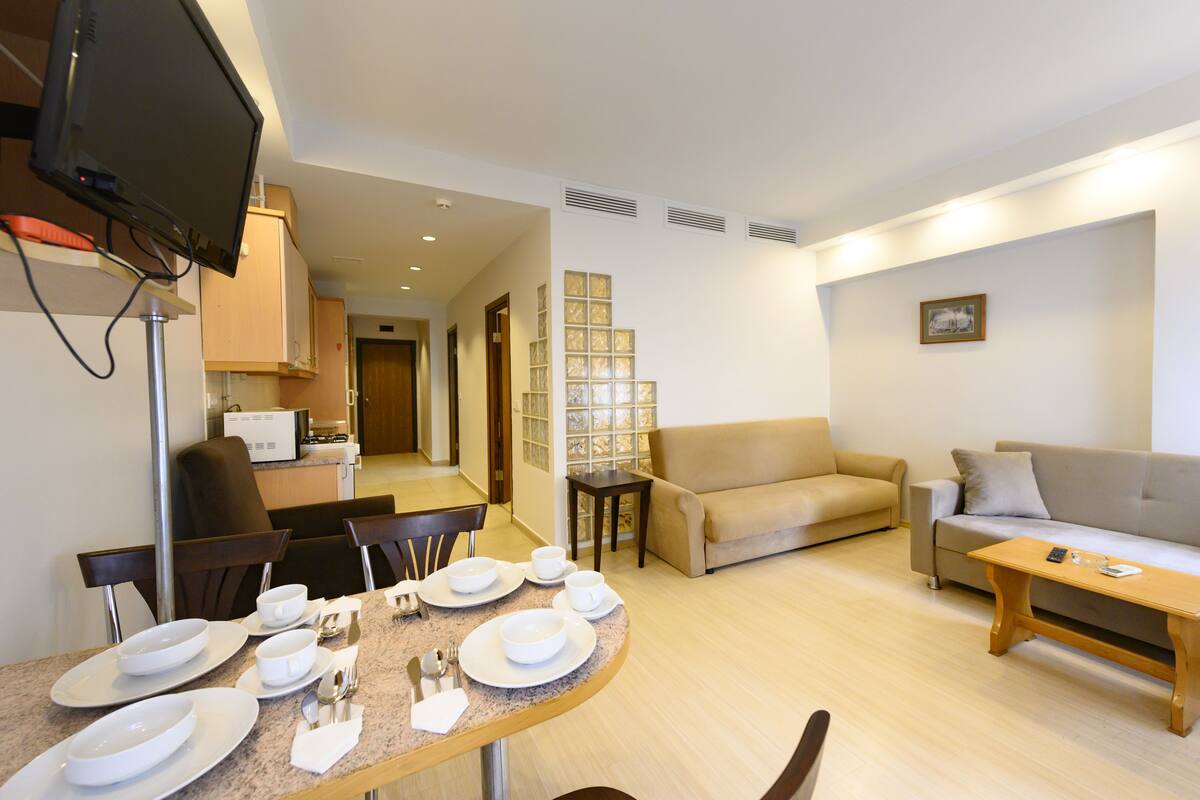 A modern living room with a dining area, a sofa, and a television.