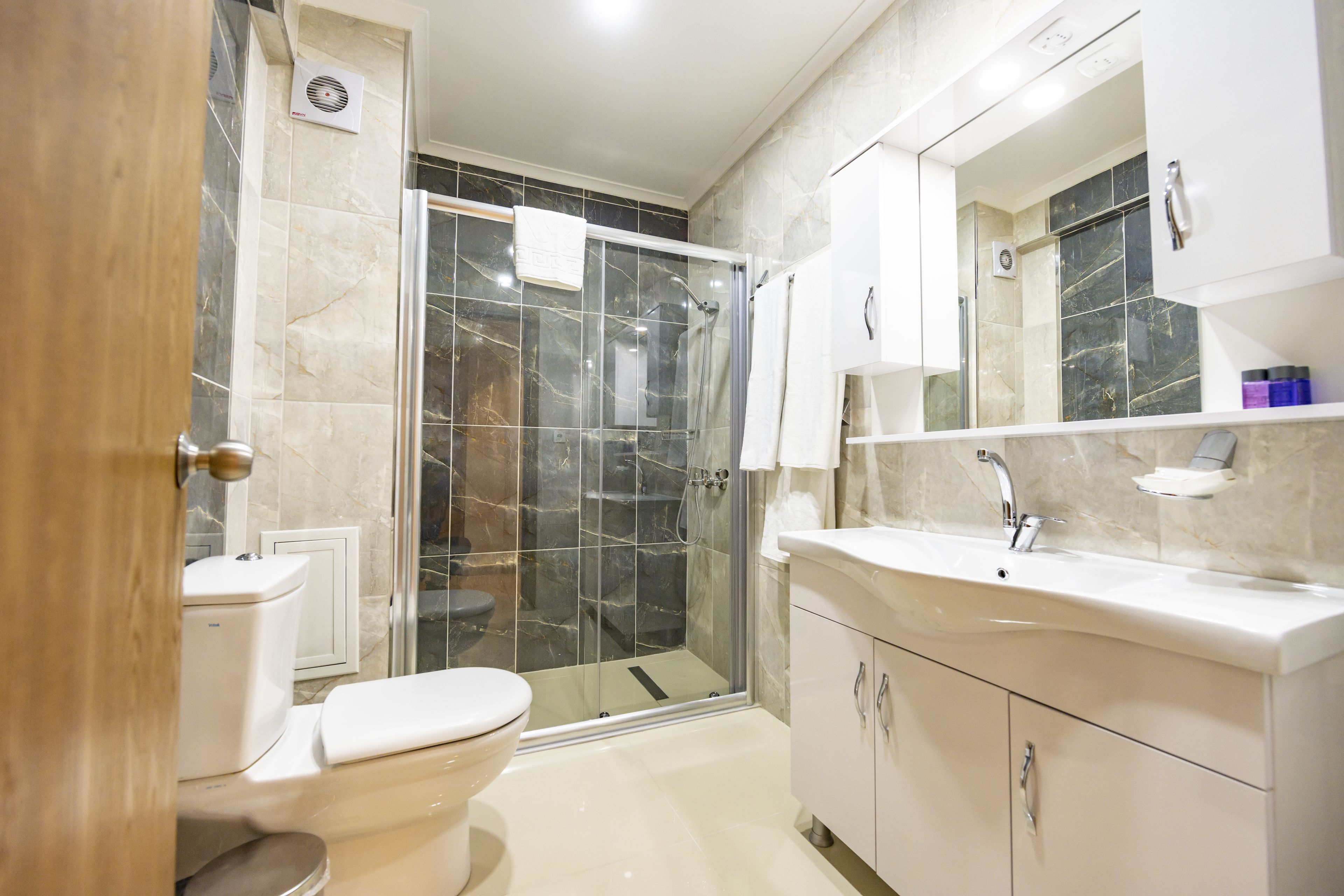A modern bathroom with a toilet, shower, and vanity.