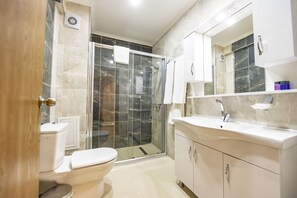 A modern bathroom with a toilet, shower, and vanity.