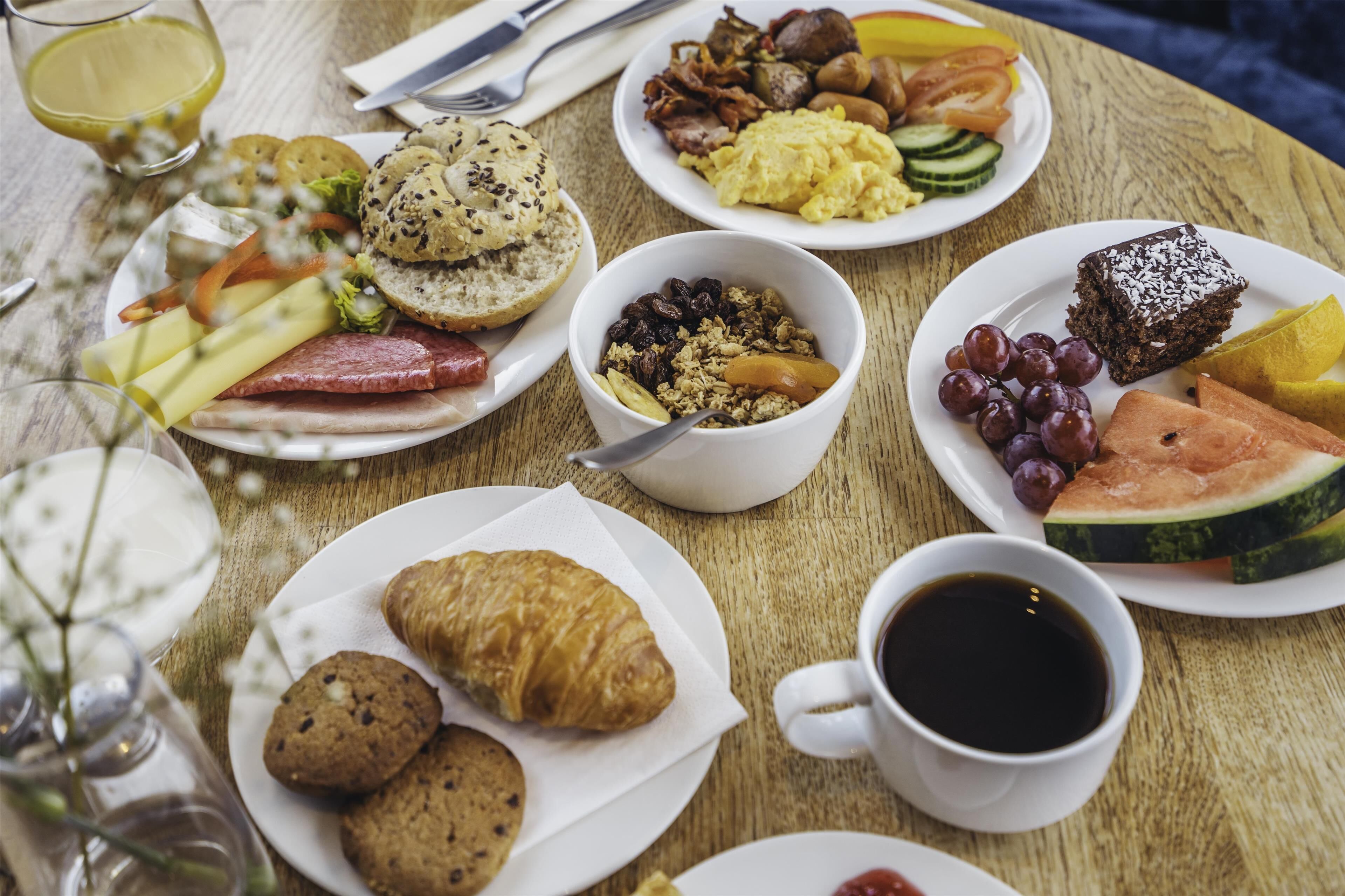 A breakfast table with various dishes including eggs, sausages, and pastries.