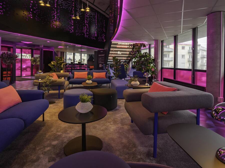 A modern lobby with sofas, tables, and potted plants.