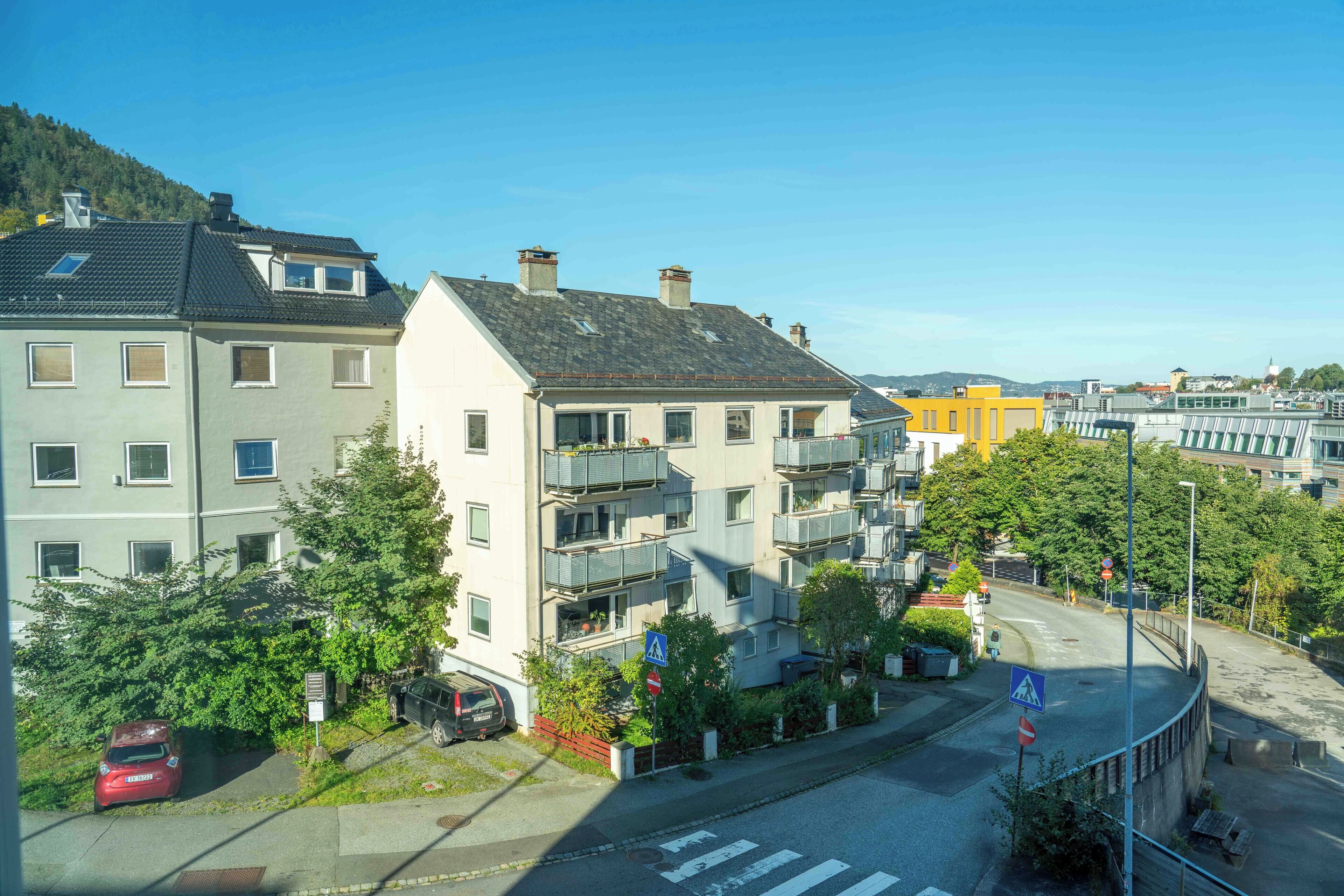 A residential building with multiple balconies, a pedestrian crossing, and a clear sky.