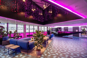 En moderne lobby med et geometrisk gulvmønster, blå siddepladser og en receptionsdisk.