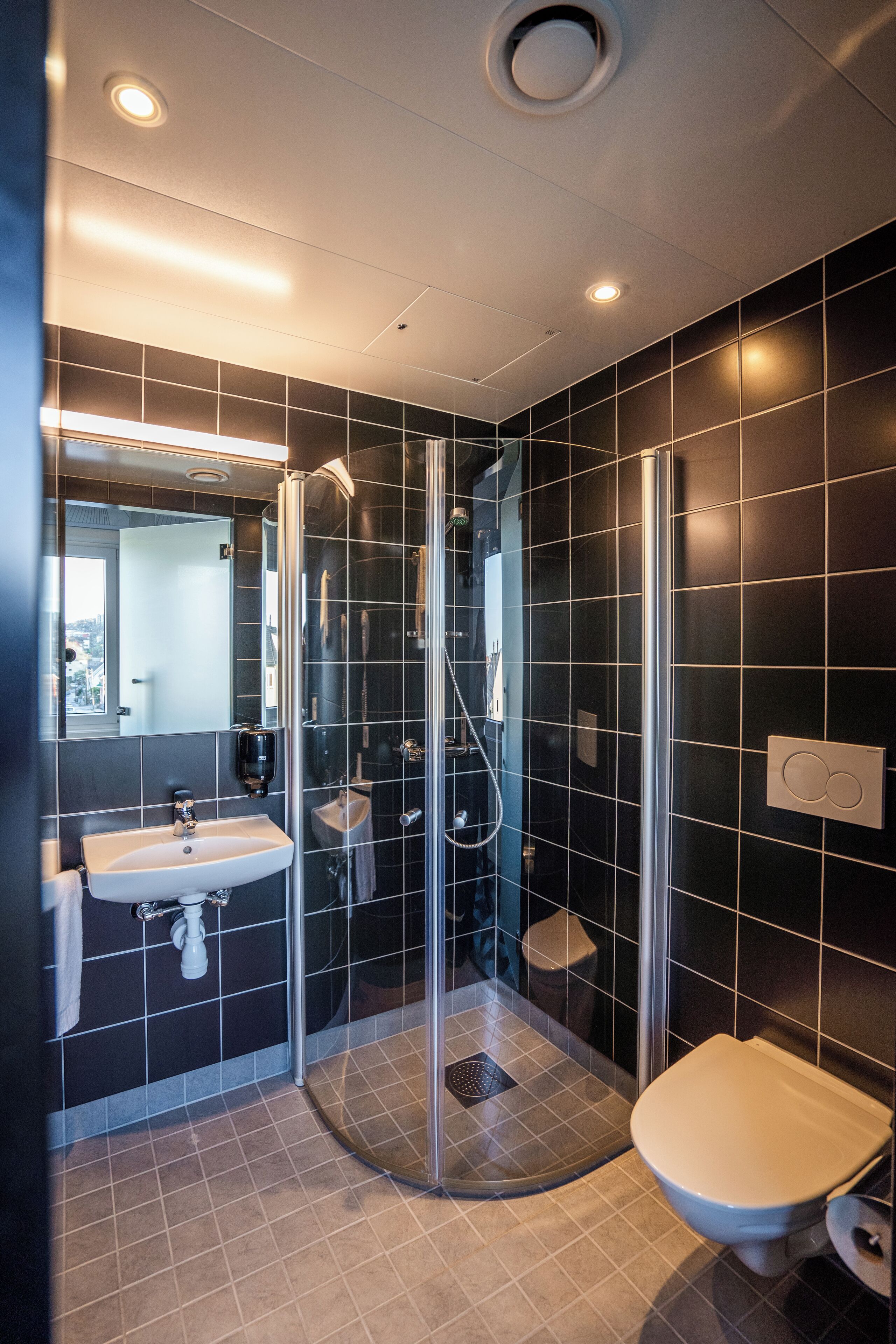Een moderne badkamer met een douchecabine, een wastafel en een toilet.