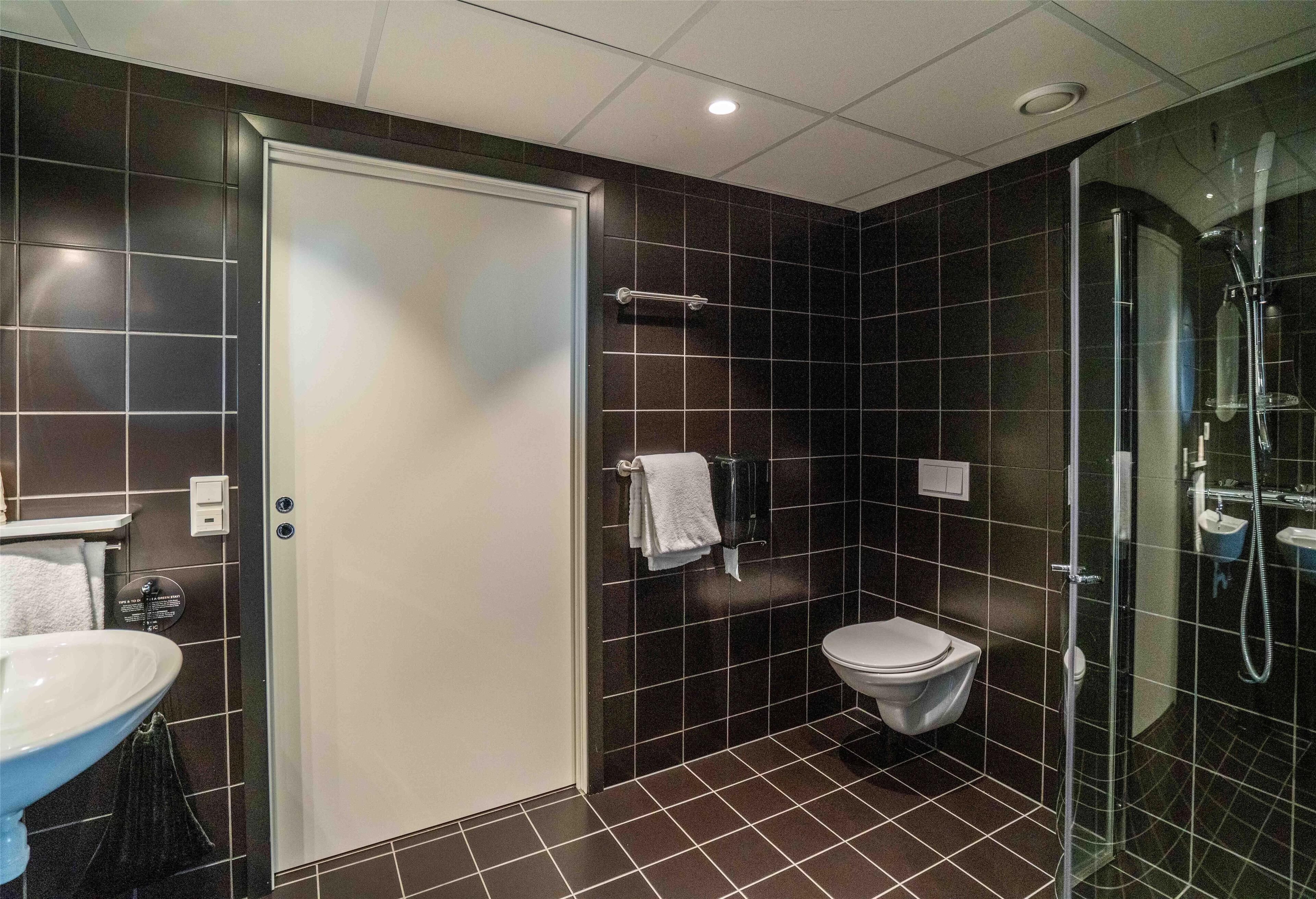 A modern bathroom with a white toilet, a glass-enclosed shower, and a sink with a towel rack.