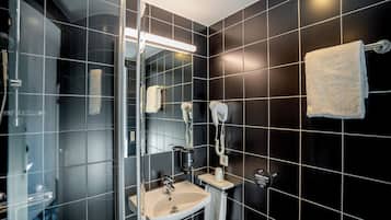 Un baño moderno con cabina de ducha de vidrio, un lavamanos y un perchero para toallas.