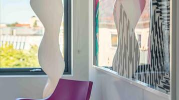 A modern interior with two purple chairs, a white abstract sculpture, and a colorful geometric wall art piece.