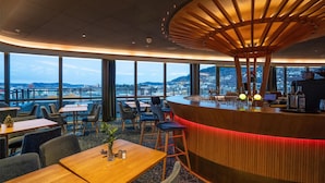 A modern restaurant with a curved bar, large windows offering city views, and a mix of seating arrangements. - Prize by Radisson, Solheimsviken Bergen (Bergen)