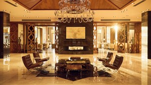 A spacious lobby with a large chandelier, a fireplace, and leather seating. - Chenot Palace Gabala (Gabala)