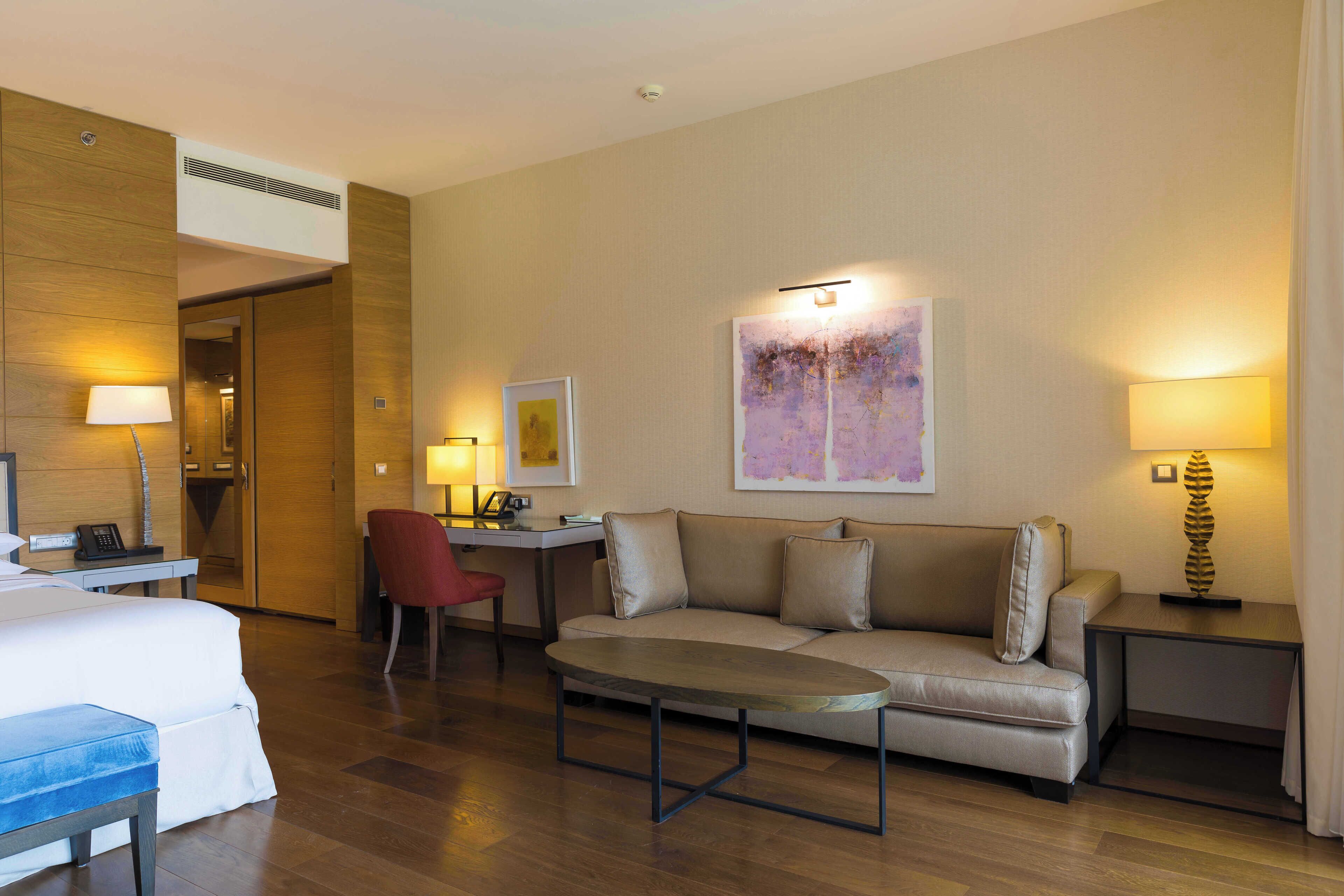 A hotel room with a bed, a sofa, a desk, a chair, and a coffee table.