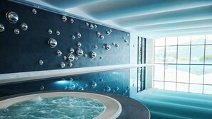 A modern spa room with a hot tub and a wall of circular mirrors. - Chenot Palace Gabala (Gabala)