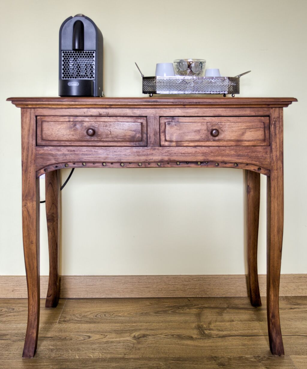 A wooden desk with two drawers and a metal object on top.