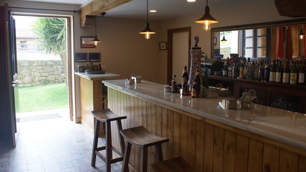 Een bar met houten barstoelen, een toonbank met flessen en hangende吊り灯.