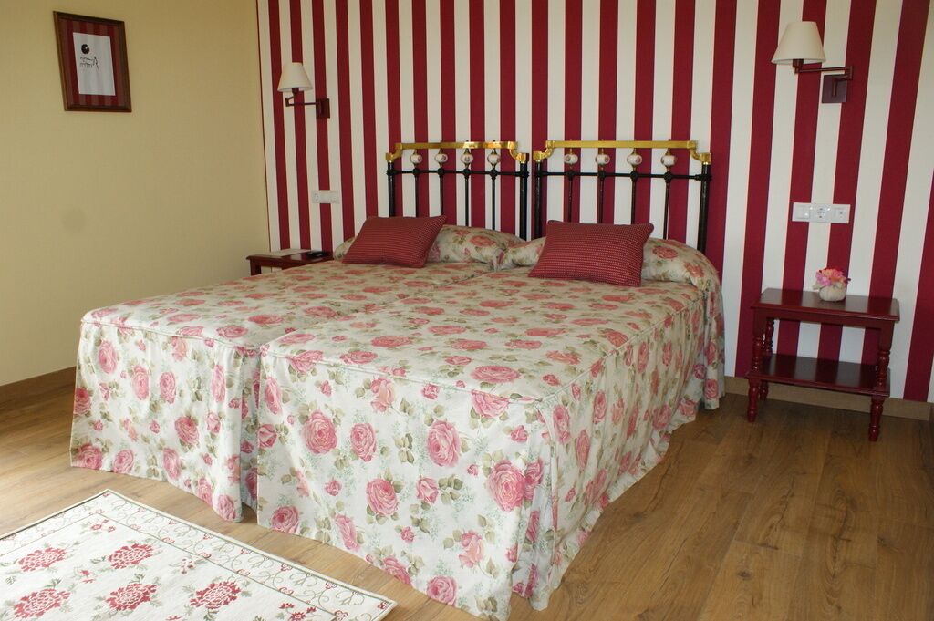 Un dormitorio con una cama, papel tapiz a rayas, una mesita de noche y una lámpara.