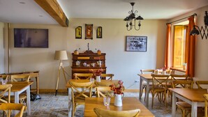 Een eetgedeelte met houten tafels en stoelen, een buffet en kunstwerken aan de muur.