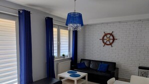 A modern living room with a black sofa, a white coffee table, and a blue pendant light. - Family Homes - Apartamenty Rzemieślnicza (Władysławowo)