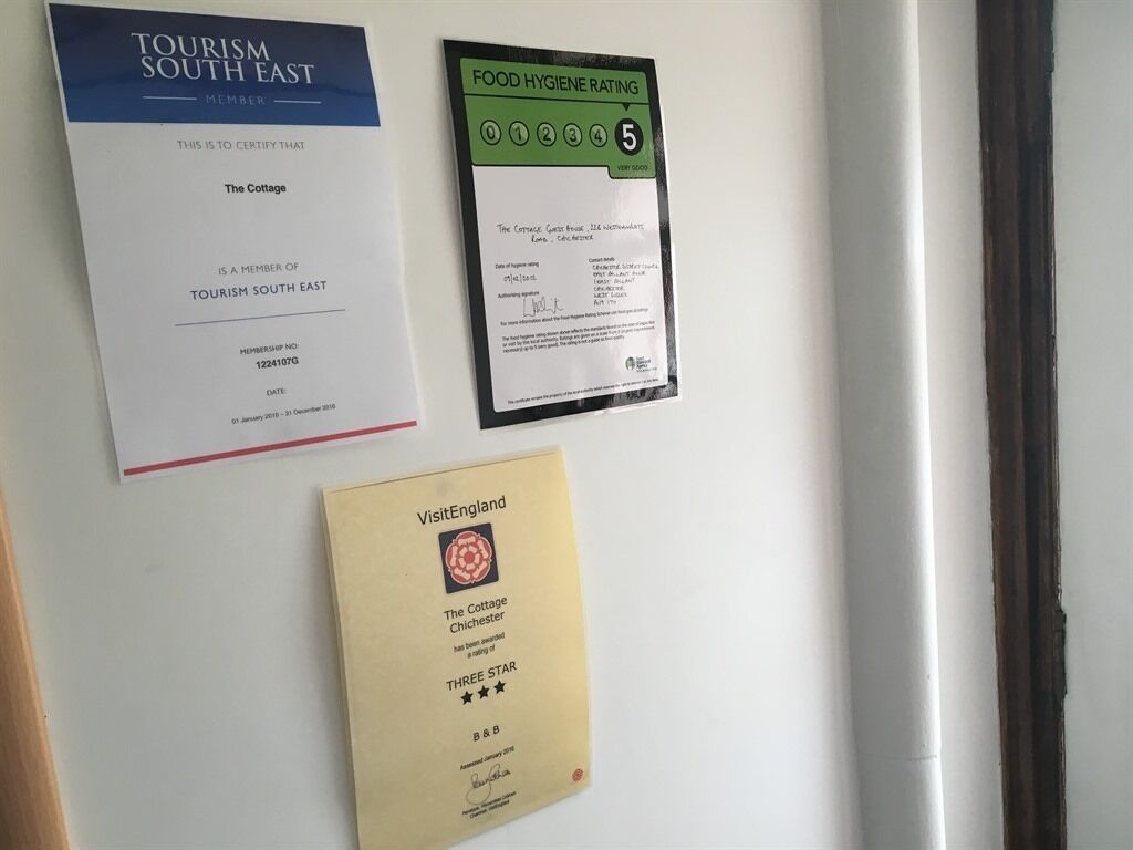 A wall with three documents: a Tourism South East membership certificate, a food hygiene rating, and a VisitEngland three-star award.