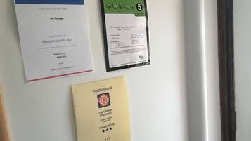 A wall with three documents: a Tourism South East membership certificate, a food hygiene rating, and a VisitEngland three-star award.