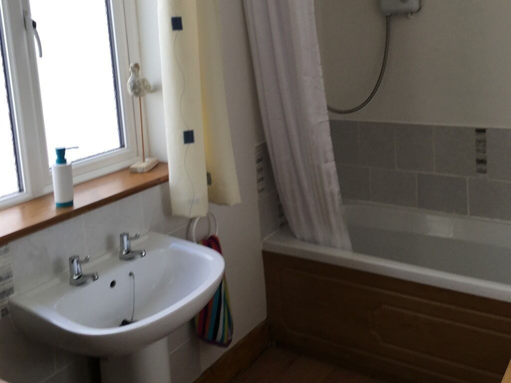 A bathroom with a sink, a window, and a bathtub.