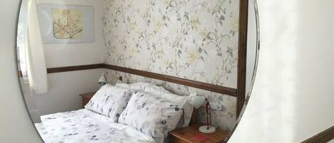 Un dormitorio con cama, mesita de noche y lámpara de pared.