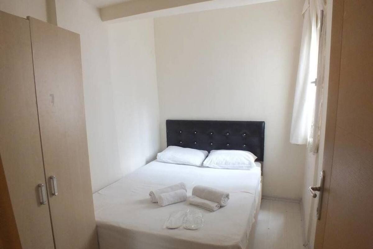A bedroom with a bed, white linens, a black headboard, and a door with a handle.
