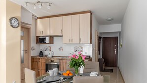 Eine moderne Küche mit Holzschränken, einer Mikrowelle und einem Essbereich mit Tisch für zwei Personen.
