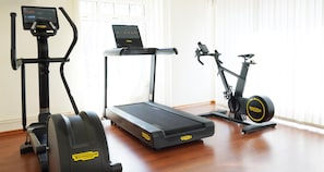 A home gym with a treadmill, elliptical, and stationary bike. - Best Western Hotel St. Michael (Morbach)