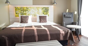 A hotel room with a large bed, a bedside table, a chair, and a small round table. - Best Western Hotel St. Michael (Morbach)