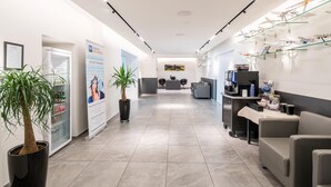 A modern reception area with a glass display of model airplanes, a reception desk, seating area, and a coffee machine. - Best Western Hotel St. Michael (Morbach)